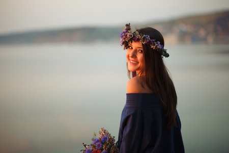 Portrait of a happy pretty woman with a bouquet of peony. On the background of the sea. Sunset lightの写真素材
