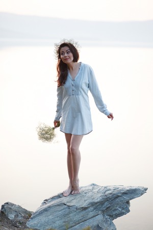 Portrait of a happy pretty woman with a bouquet of peony. On the background of the sea. Sunset lightの写真素材