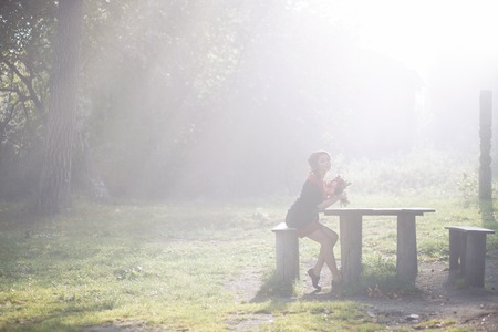 Beautiful woman in autumn park. Sun rays beating down on woman walking in forestの写真素材