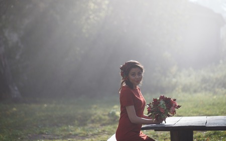 Beautiful woman in autumn park. Sun rays beating down on woman walking in forestの写真素材