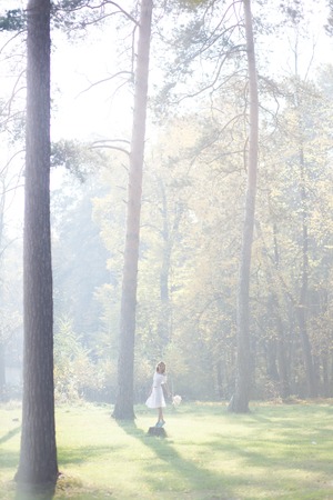 Lovely bride outdoors in a forest. Sun rays beating down on woman walking in forestの写真素材