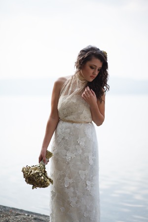 Portrait of pretty bride pictured in traditional white wedding dress. She is holding a bouquet.の写真素材