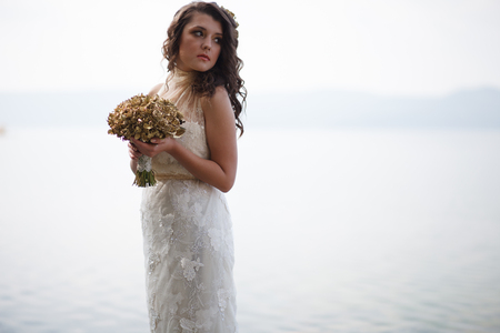 Portrait of pretty bride pictured in traditional white wedding dress. She is holding a bouquet.の写真素材