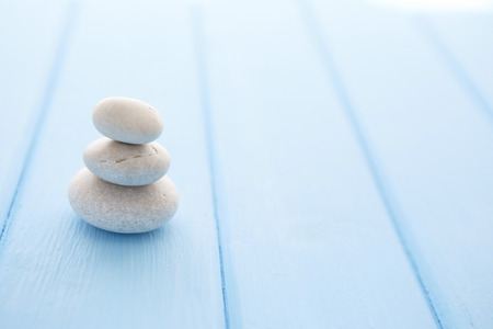 Zen stones wooden table. Pile planar stones on the old blue wooden rustic table.の写真素材