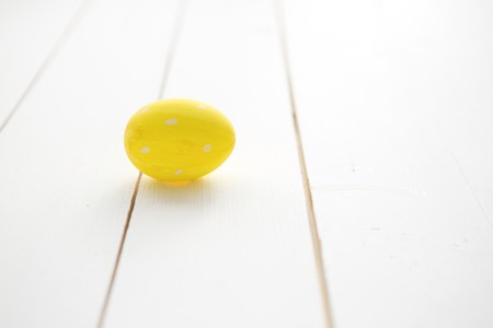 One yellow Easter egg on white wooden background. Happy Easter.の写真素材