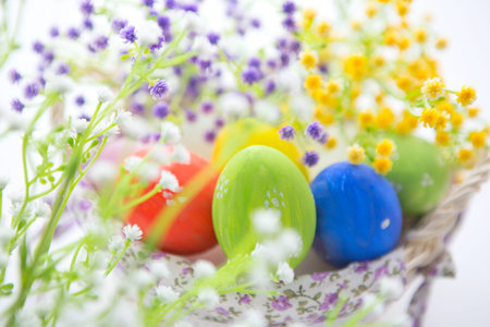 Beautiful flowers and easter eggs basket. Easter eggs in basket on wooden surface.の写真素材