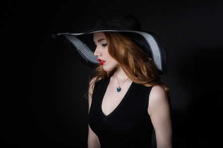 Beautiful Woman in big black hat on dark backgroundの写真素材