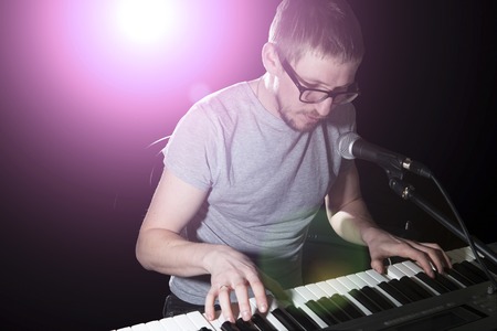 keyboarder is playing and singing on dark backgroundの写真素材