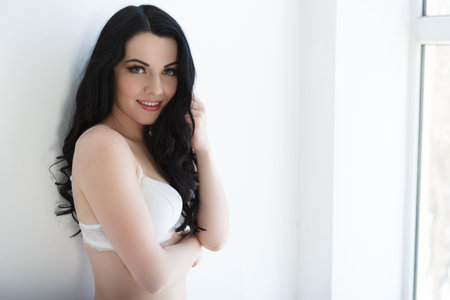 Sensual attractive brunette woman posing over the window wearing sexy lingerie. Slim girl.の写真素材