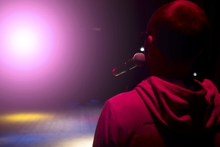 Singer holding a microphone and singing on black dark background.の写真素材