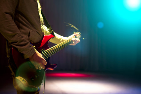 Man staying on stage and playing electric guitar on black dark background.の写真素材