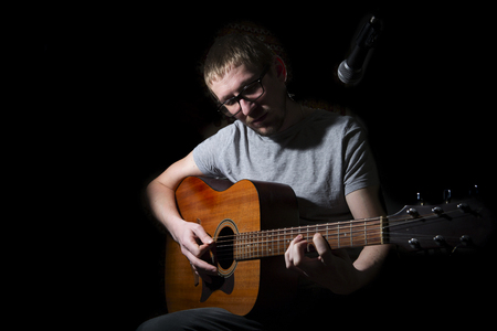Musician playing on acoustic guitar on dark backgroundの写真素材