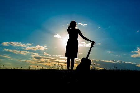 Women with guitar over sunset sky, Selective Focus. Silhouetteの写真素材