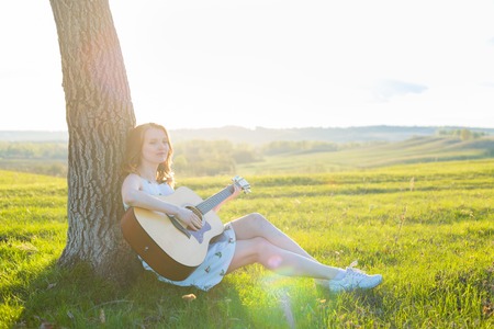 Girl sitting with acoustic guitar at field Copy space for inscriptionの写真素材