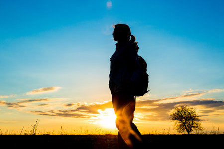 Girl hiking in silhouette in the sky colored