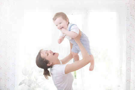 Young mother holding her newborn child. Mom nursing baby. Woman and new born boy relax in a white...