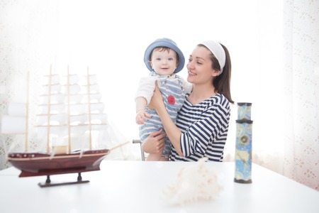 Happy kid and mom playing with toy sailing boat indoors. Travel and adventure conceptの写真素材