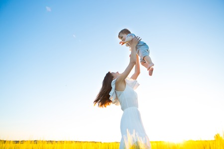 Happy family on nature outdoors mother and baby son on the green meadowの写真素材