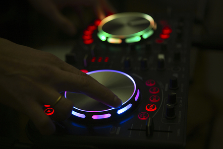 DJ console mixer controlling with two hand in nightclub.の写真素材