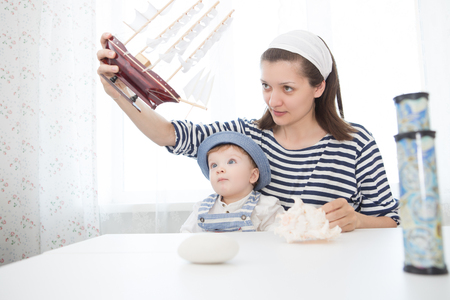 Travel concept. Happy sailor kid and mom playing indoors. Travel and adventure concept. Summer vacationの写真素材