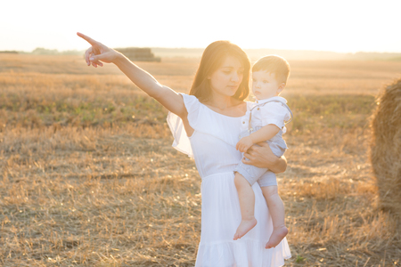 Happy mother and her little son in the field. Mom points to something with your finger.の写真素材