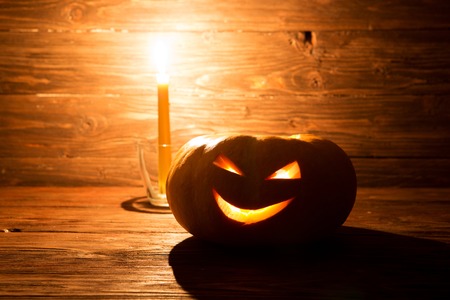Jack o lanterns Halloween pumpkin face with candle on wooden background.の写真素材