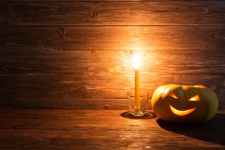 Jack o lanterns Halloween pumpkin face with candle on wooden background.の写真素材