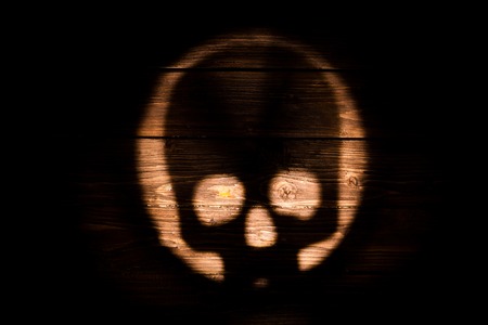 Silhouette human skull on dark wooden backgroundの写真素材