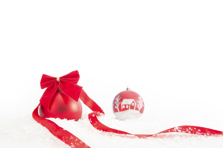 Red Christmas ball with ribbon on snow on white backgroundの写真素材