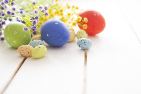Beautiful Easter eggs and flowers on white wooden background, closeupの写真素材