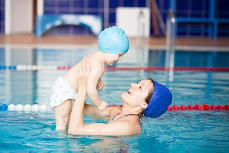Healthy family mother teaching baby swimming pool. The concept of happiness and love.の写真素材
