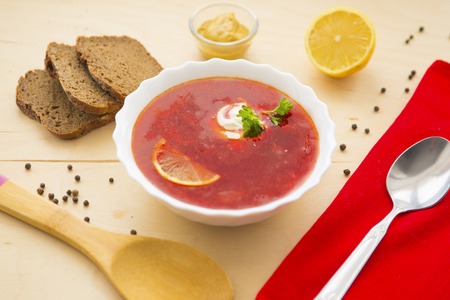Borscht with sour cream and dark bread on wooden tableの写真素材