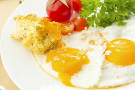 Fried eggs with white bread on plate on wooden tableの写真素材