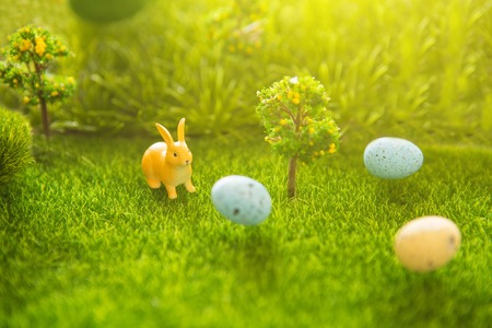 Easter decorate with rabbit toy and Easter eggs on grass field background.の写真素材