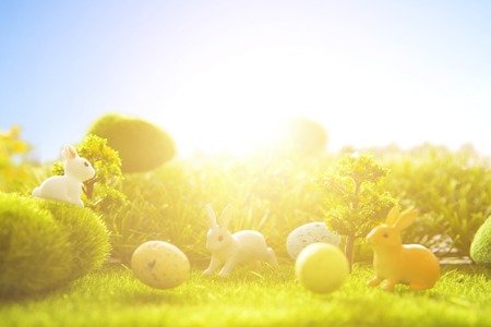 Easter eggs with easter bunny toys on green grass meadow on sunset. Holiday concept. Happy Easter.の写真素材