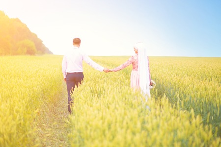 Smiling young islamic couple portrait on wheat field. Muslim marriage.の写真素材