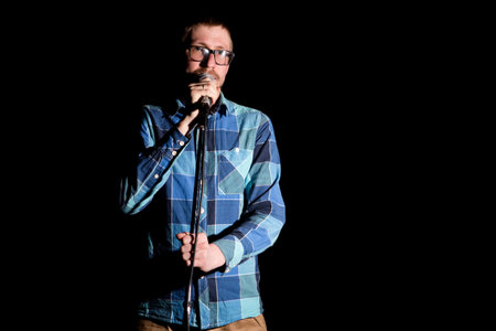Singer man in plaid shirt singing with microphone.