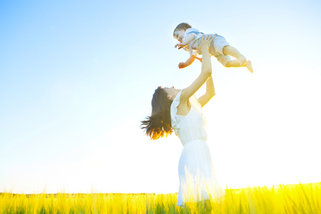 Happy young family outdoor on a summer day in wheat field over sunset.の写真素材