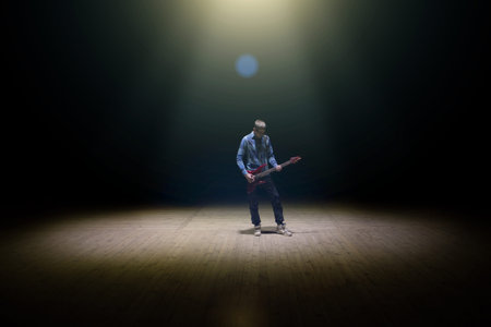 man playing electrical guitar on dark background