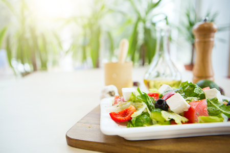 Fresh Greek salad on a plate on wooden cutting board.の写真素材