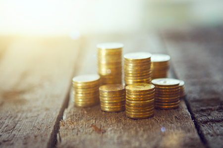 Gold money coins pile on wooden table.の写真素材