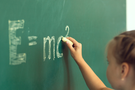 Girl drawing on chalkboard formula e=mc2. Education and school concept.の写真素材