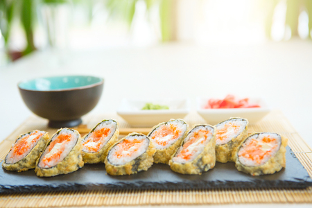 Hot sushi rolls served on black slate surface. Japanese food.の写真素材