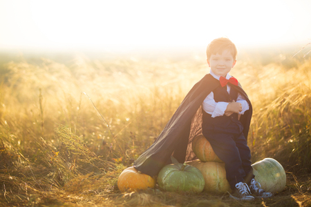 Happy child boy dressed as a dracula with pumpkins on sunset. Halloween.の写真素材