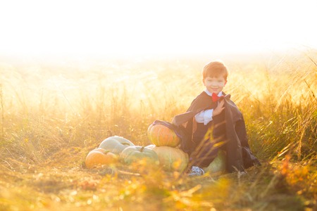 Happy young boy dressed as a dracula with pumpkins for Halloween.の写真素材