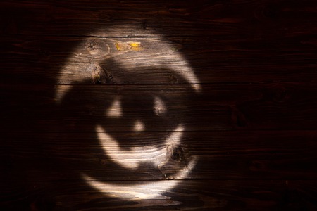 Black or dark laughing pumpkin Halloween Jack-o'-lantern of shadow on a dark wooden background. Jackolantern.の写真素材