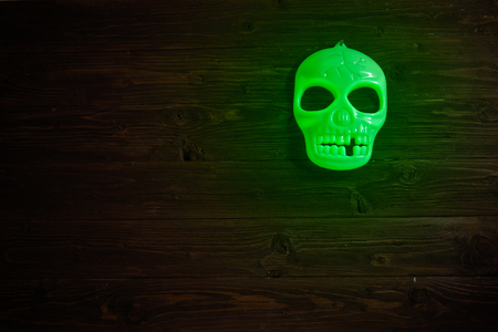 Halloween glowing phosphoric human skull over wooden table background. Neon light.の写真素材
