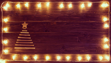 Christmas lights with a Christmas tree of dried branches on a wooden background.の写真素材
