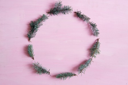 Christmas composition. Christmas round frame made of fir tree branches on pink background with copy space. Top view.の写真素材