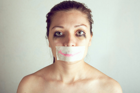 Unhappy woman with wrapping her mouth by adhesive tape painted smile.の写真素材